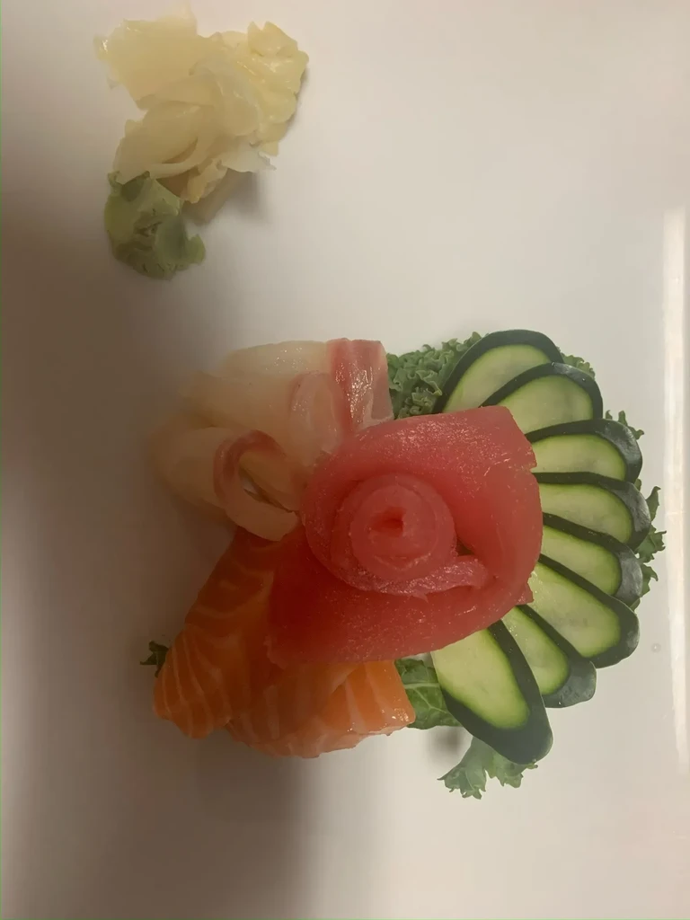 Plated sashimi assortment: salmon, tuna, white fish, ginger, and wasabi.