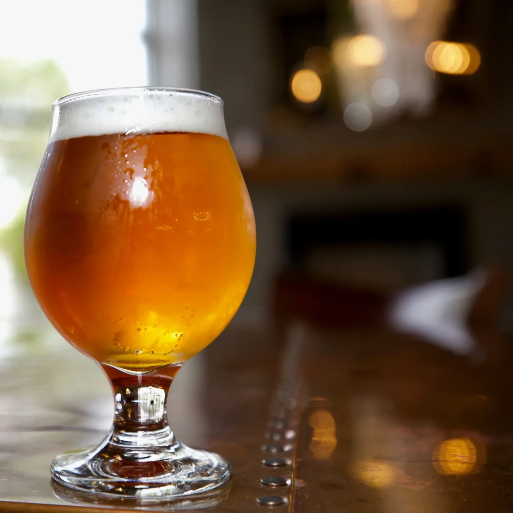 Close-up of a cold amber beer with foam on a bar.
