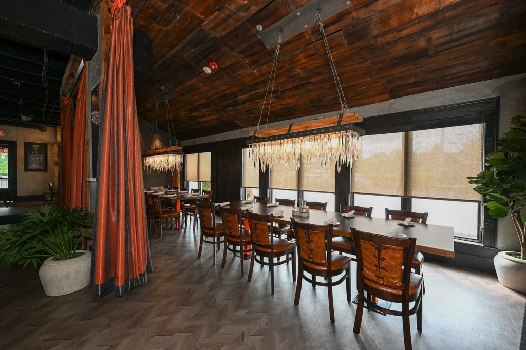 Private dining room with dark wood ceiling, crystal chandeliers, and orange drapes.