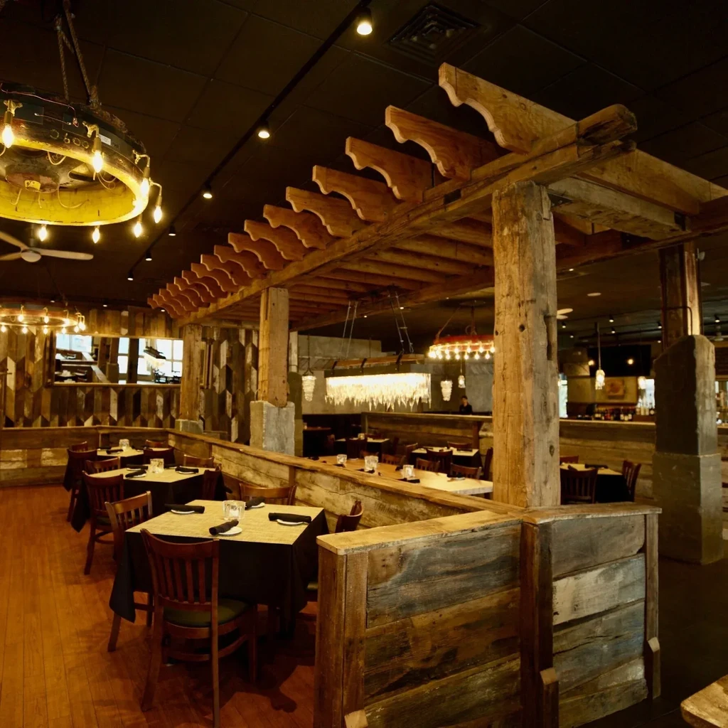 Rustic-industrial restaurant interior with warm lighting and a large wooden pergola.