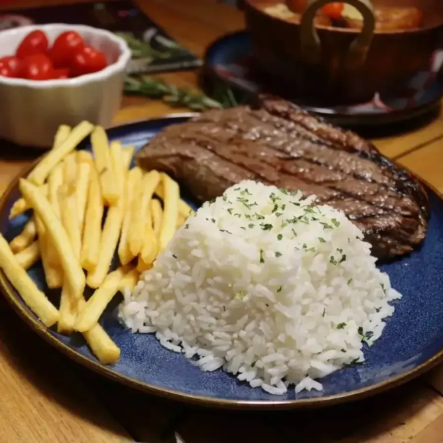 Grilled steak, french fries, and herb rice on a blue plate.
