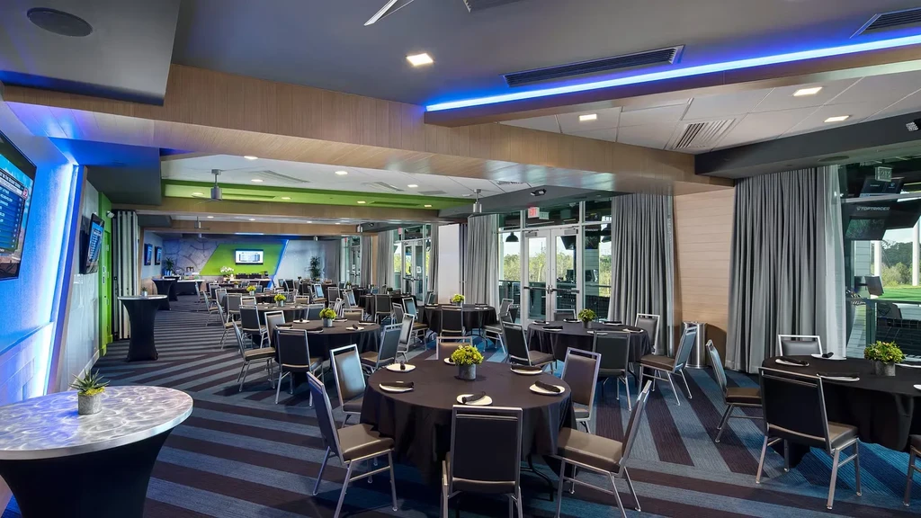 Empty, modern dining and event space overlooking a Toptracer golf range.