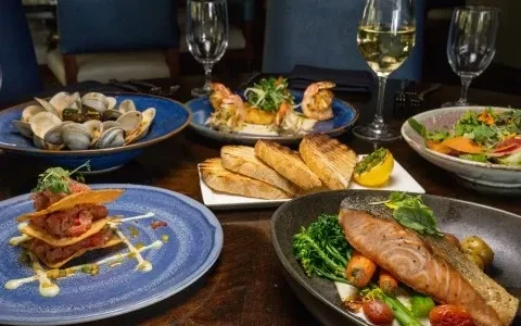 Table laden with gourmet dishes, featuring seafood and white wine.