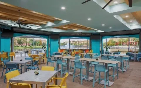 Empty modern restaurant with yellow and blue furniture overlooking a lake.