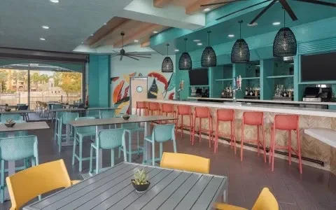 Vibrant tropical restaurant interior with abstract mural and scenic water view.