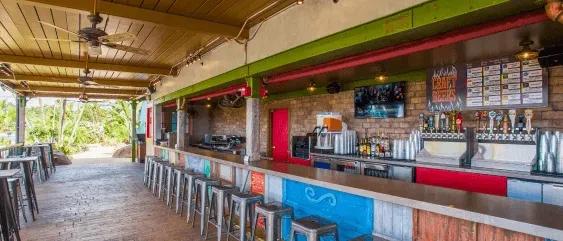 Vibrant outdoor bar with colorful counter, menu, and tropical patio.