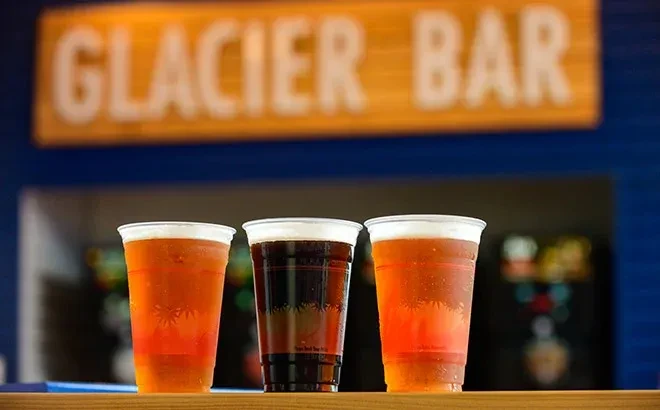 Three plastic cups of cold beer, two amber, one dark.