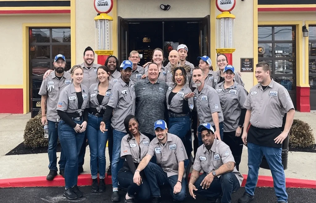Ford's Garage staff in uniforms pose outside retro restaurant.