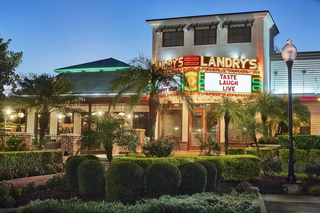 Exterior of Landry's restaurant at dusk with illuminated signs and tropical landscaping.