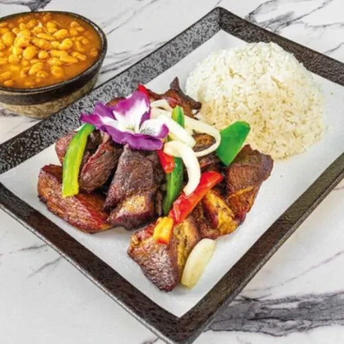 Plated dark meat, white rice, and beans, with colorful vegetable garnish.