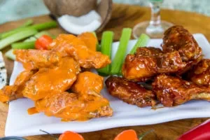 Two piles of chicken wings: orange buffalo and dark BBQ, with celery.