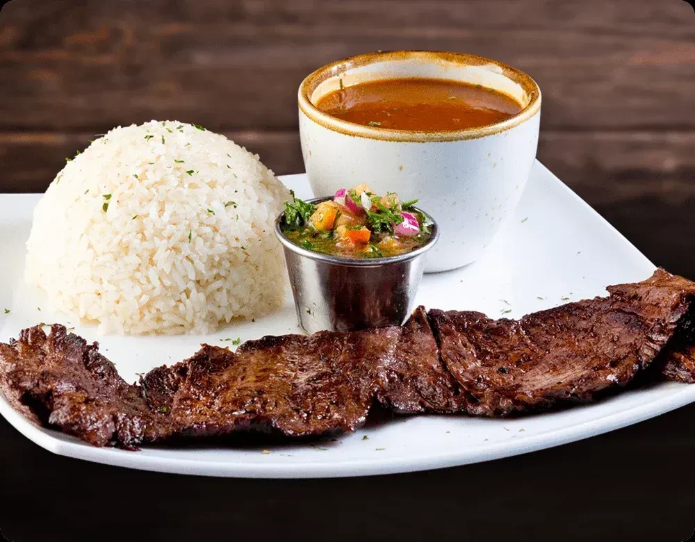 Grilled steak, white rice, salsa, and stew on a white plate.