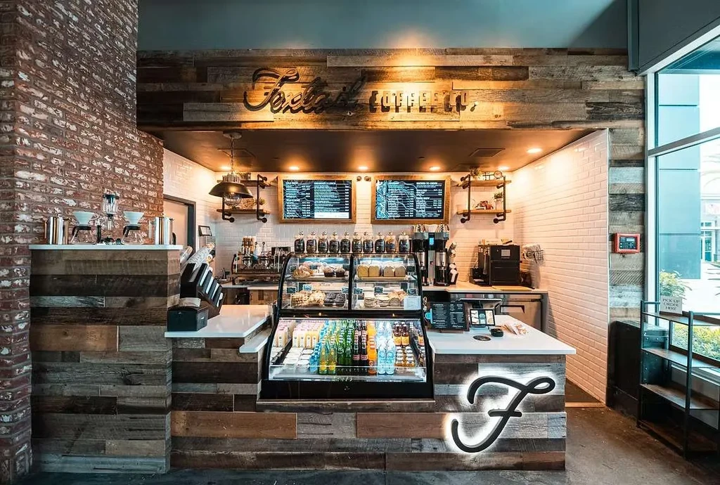 Foxtail Coffee Co. counter: wood paneling, brick, digital menus, and pastries.