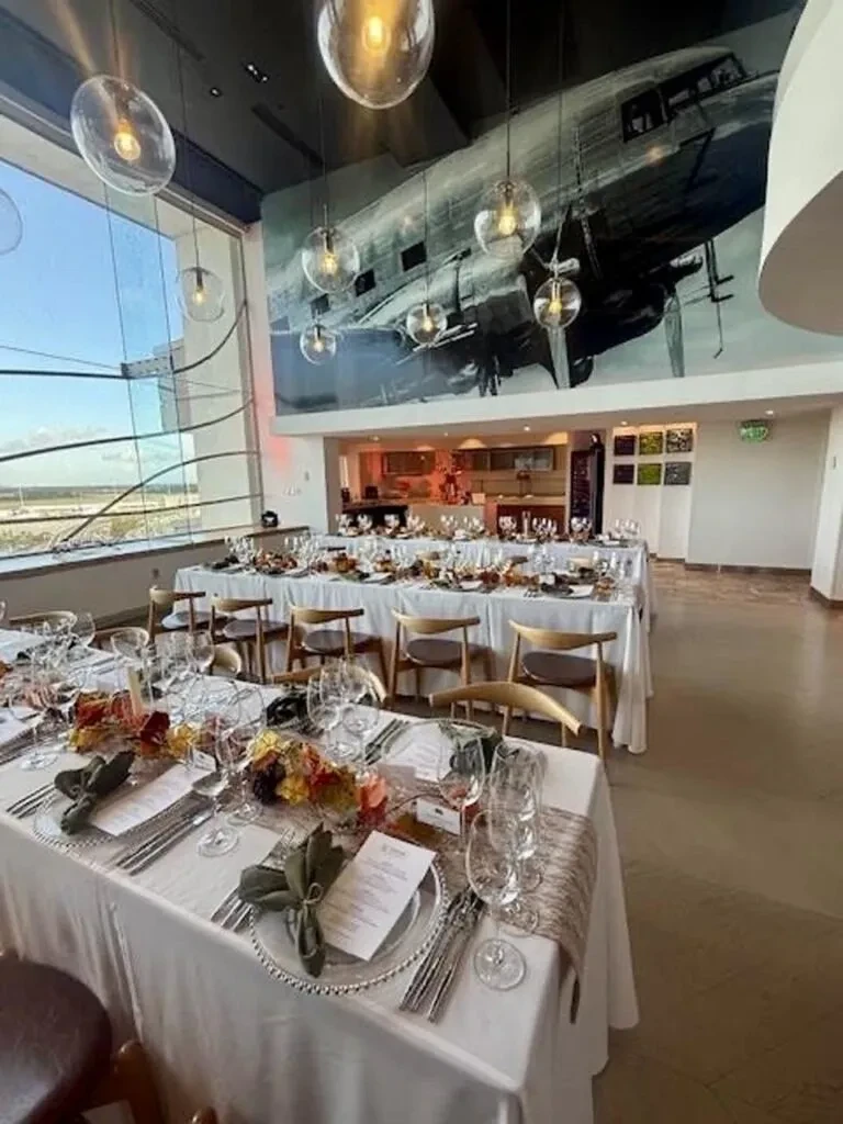 Empty modern venue with elegant autumn table settings and airplane mural.
