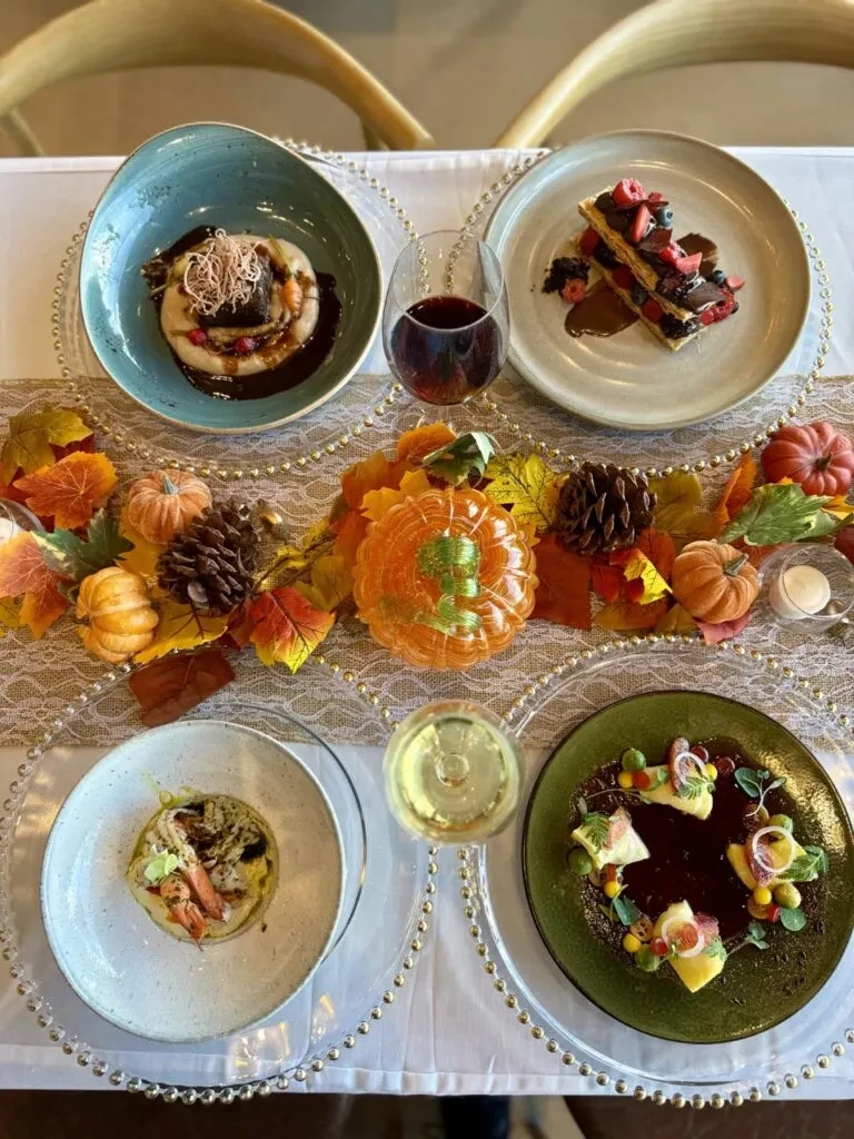 Overhead view of a dining table with gourmet dishes and autumn decor.