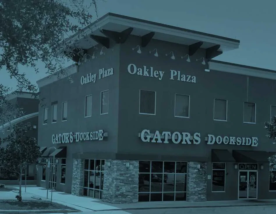 Two-story Oakley Plaza building with GATORS DOCKSIDE, strong blue-grey filter.