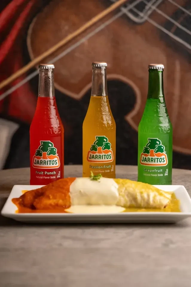 Plate with two-sauce meal, cream, and three colorful Jarritos sodas.