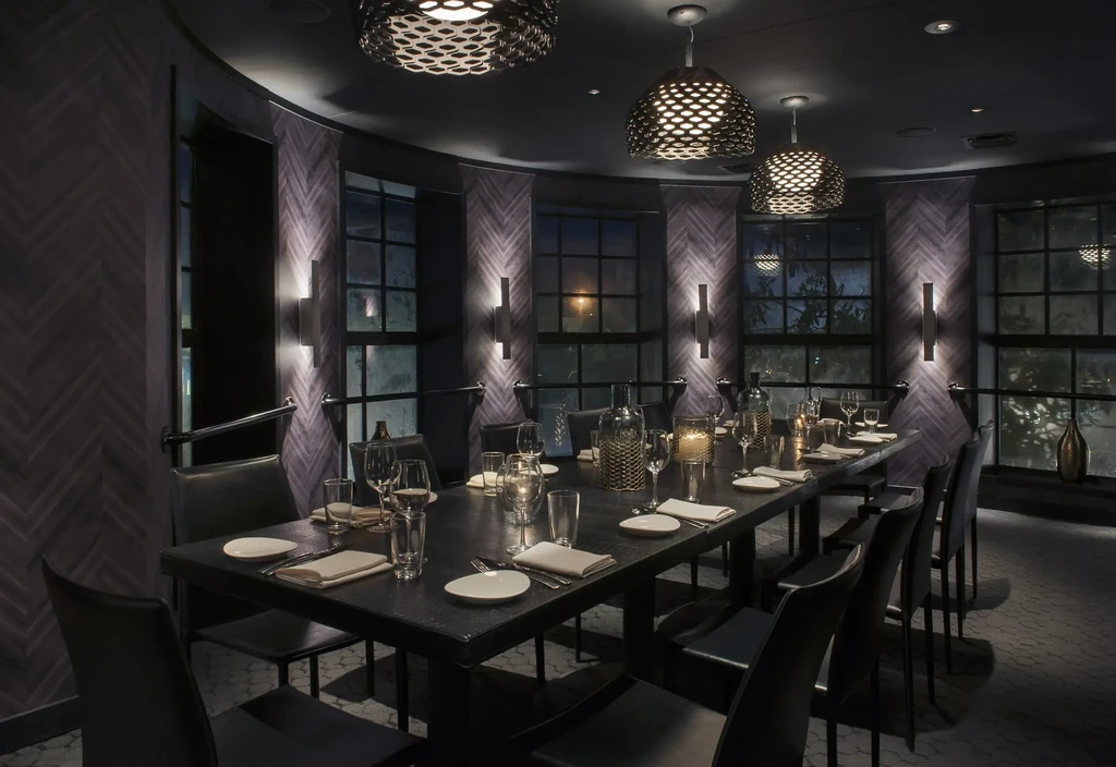 Dimly lit, elegant private dining room with a long, set table.