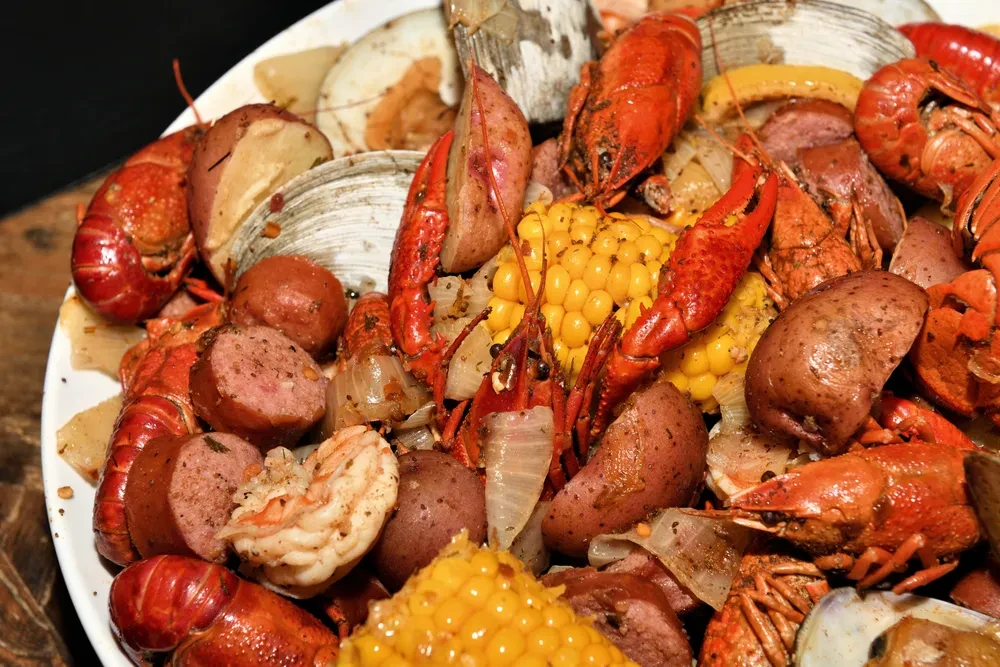 Overhead seafood boil with crawfish, corn, potatoes, sausage, clams, shrimp.