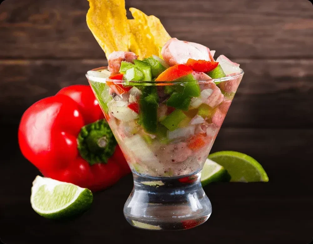 Colorful seafood dish in a glass with plantain chips and lime.