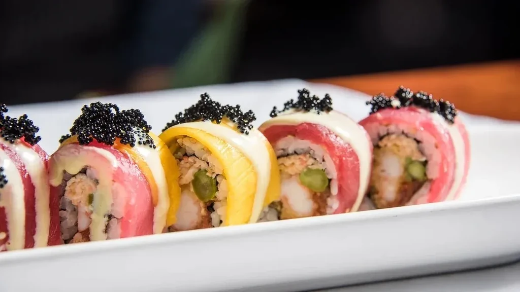 Five colorful sushi rolls with tuna, mango, caviar, and sauce.