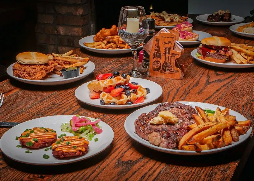 Rustic table of comfort foods: steak, fries, and waffles.