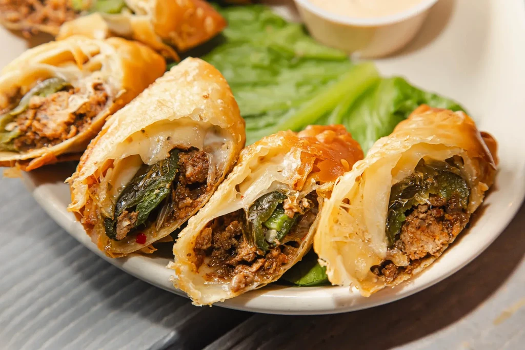 Golden deep-fried pastries with meat, cheese, chili filling, garnished with lettuce.