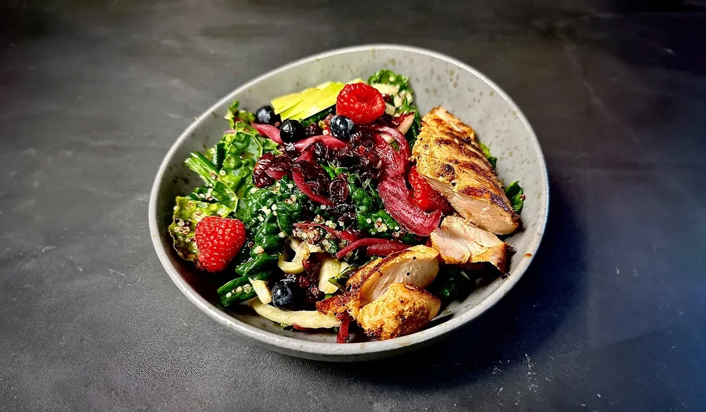 Grilled chicken salad with quinoa, berries, avocado, and red onion.