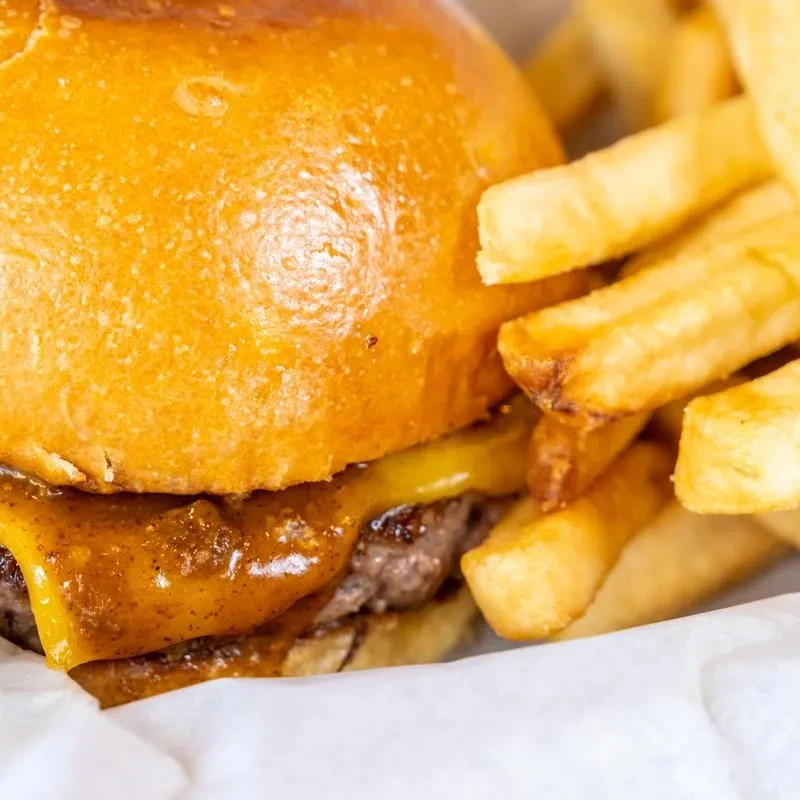 Cheeseburger with melted cheese and sauce, beside crispy golden french fries.