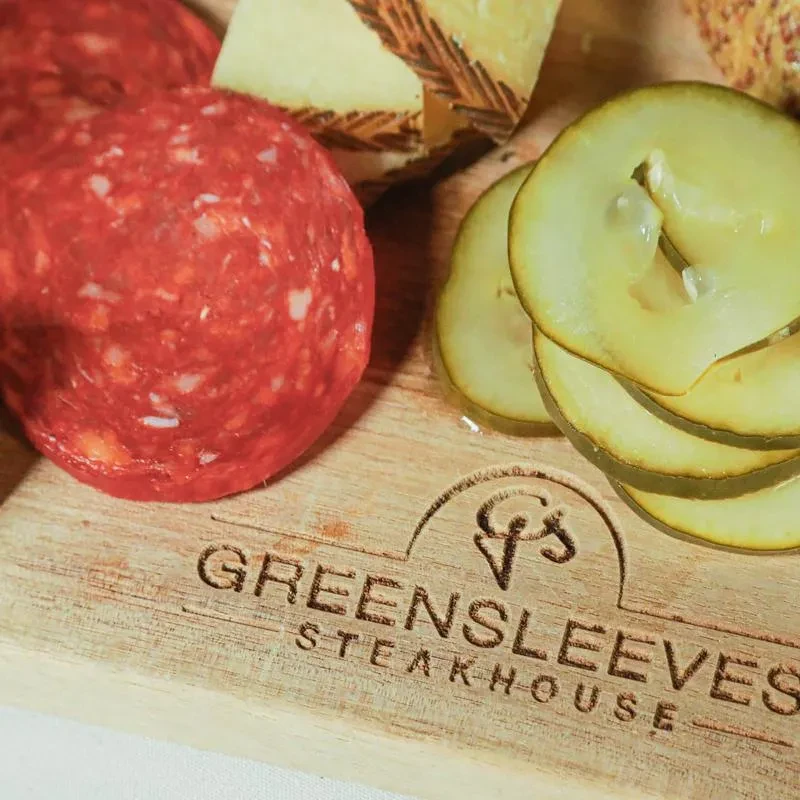 Appetizer board featuring salami, cheese, pickles, and G's Greensleeves Steakhouse logo.