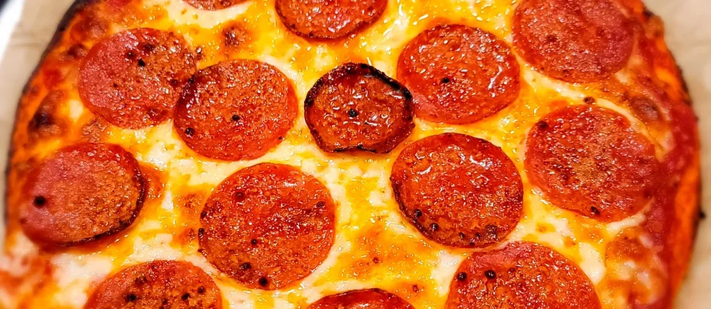 Overhead close-up of a pepperoni pizza with bubbling cheese and curled pepperoni.