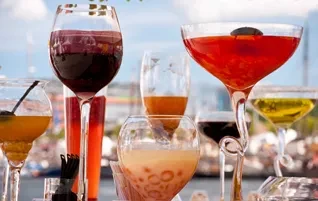 Multiple colorful drinks in various glasses at an outdoor setting.