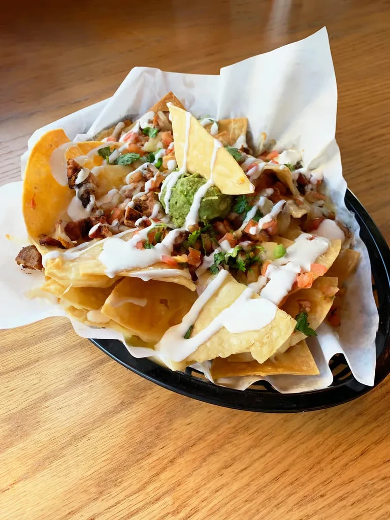 Loaded nachos with melted cheese, guacamole, pico de gallo, and chicken.