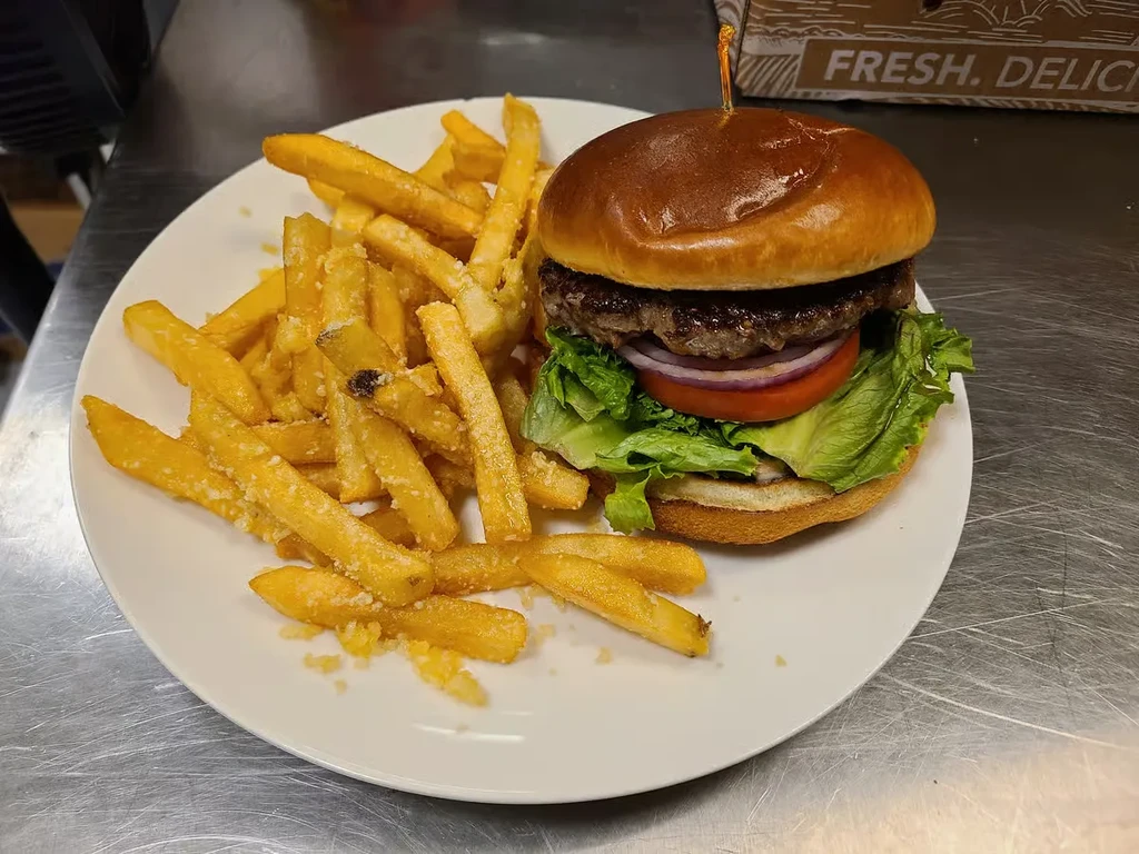 Classic brioche burger with seasoned french fries on a white plate.