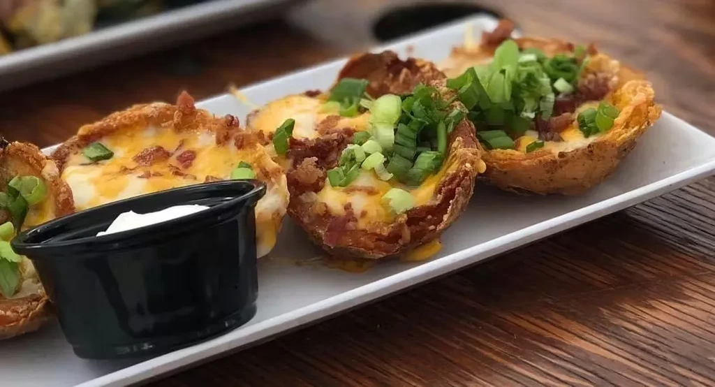 Loaded potato skins with cheese, bacon, green onions, and sour cream.