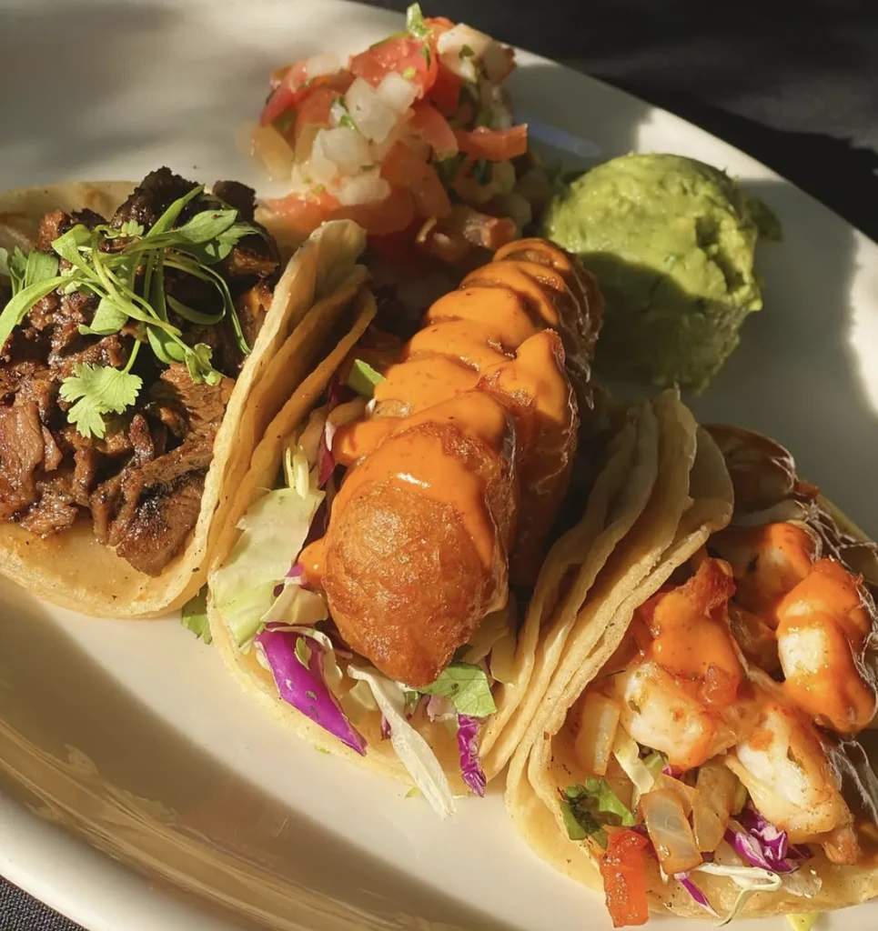 Three tacos (meat, fish, shrimp) with pico de gallo and guacamole.