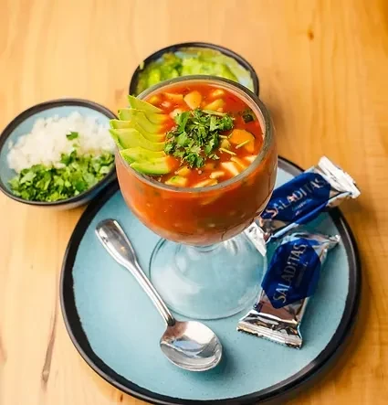 Mexican seafood cocktail in stemmed glass, with avocado, cilantro, crackers.