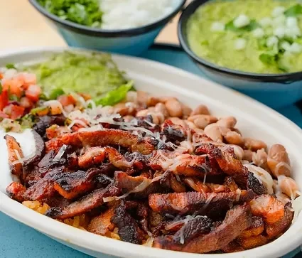 Tex-Mex bowl with grilled meat, pinto beans, guacamole, and pico de gallo.