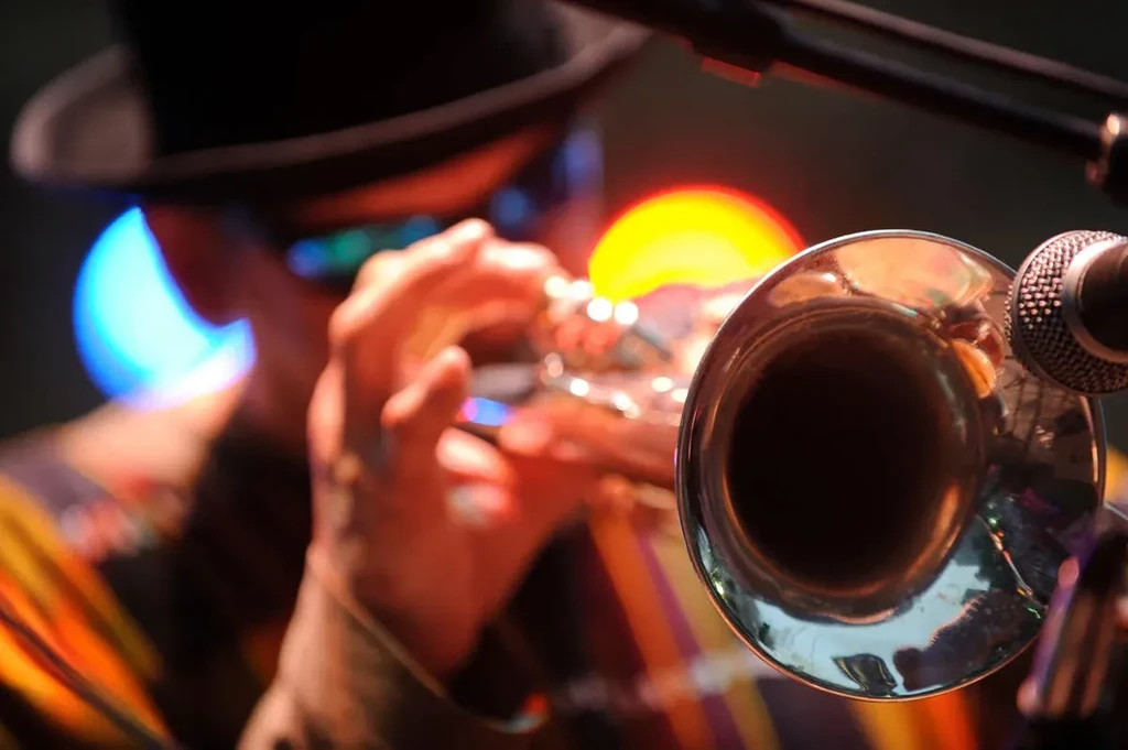 Close-up of musician playing brass instrument with microphone and bokeh lights.