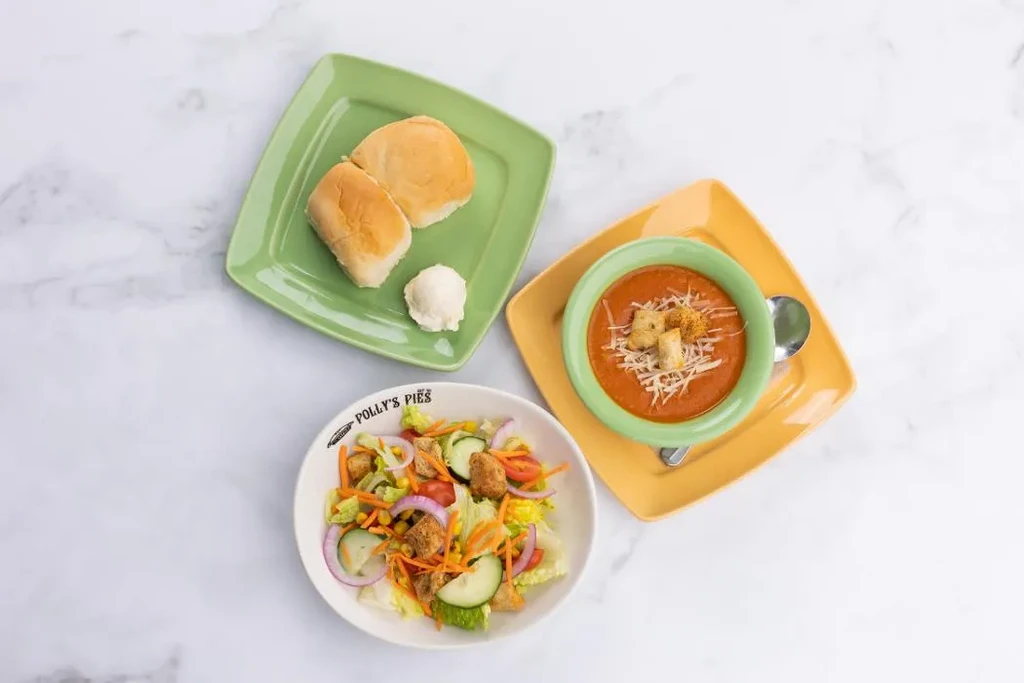Overhead meal of soup, salad, and rolls on a marble surface.