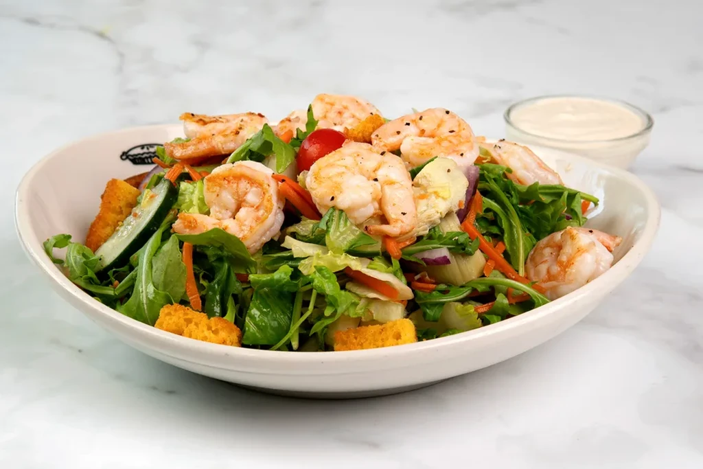 Grilled shrimp salad with mixed greens, vegetables, croutons, and dressing.