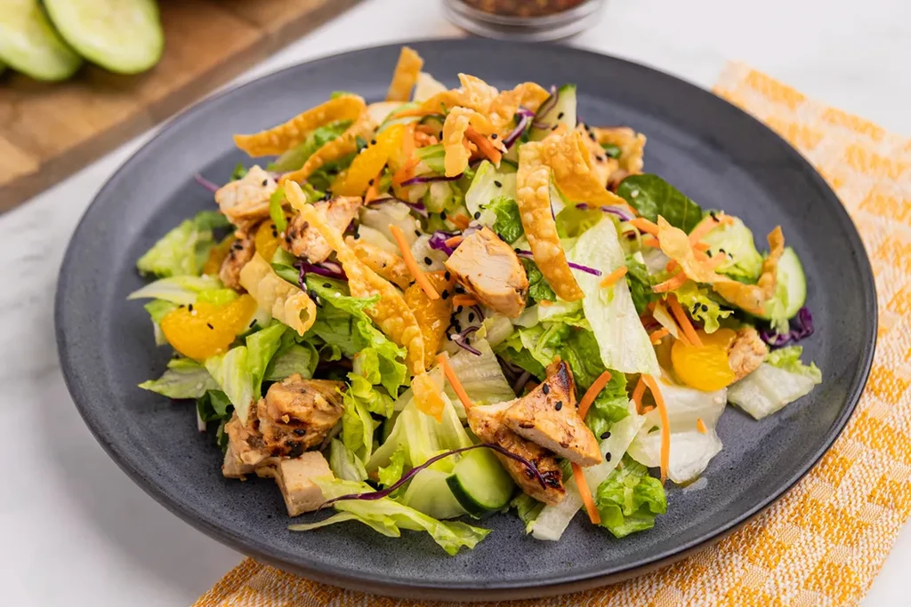 Vibrant chicken salad with mandarin oranges, wonton strips, and black sesame seeds.