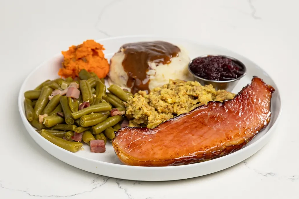 Glazed ham, mashed potatoes, sweet potatoes, stuffing, and green beans.
