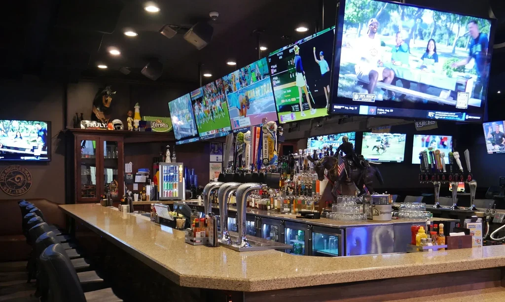 Modern sports bar with a long bar counter and many sports TVs.