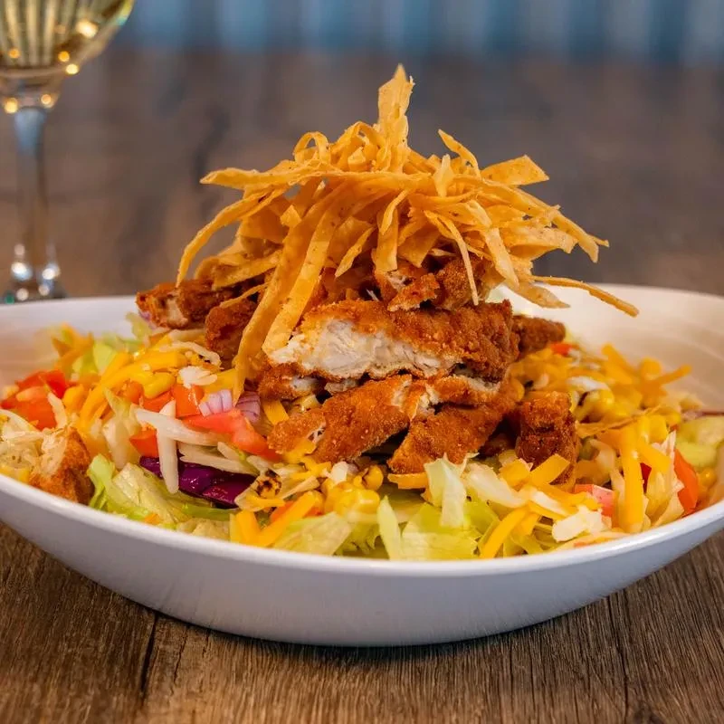 Close-up of a large salad with fried chicken and tortilla strips.