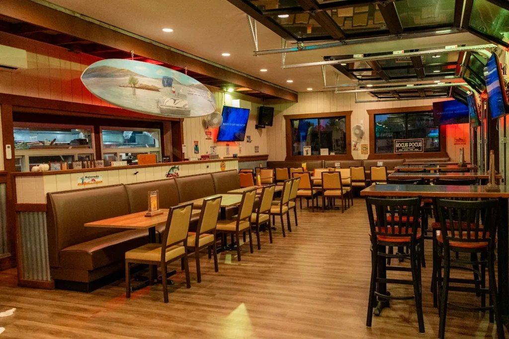 Empty casual restaurant interior with booths, tables, and a bar area.