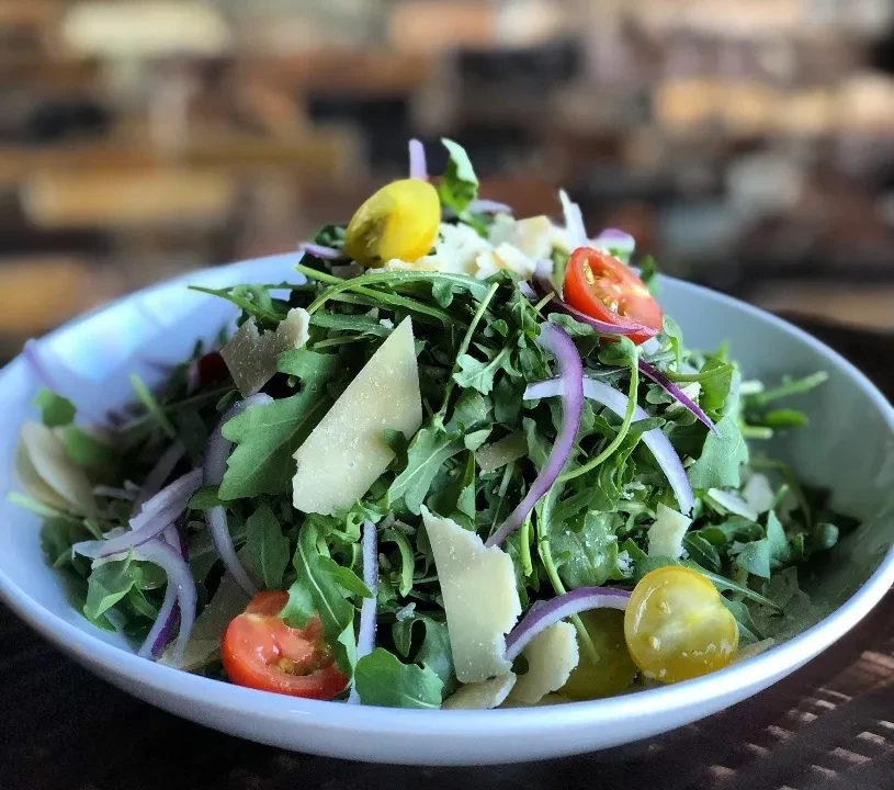 Fresh salad with arugula, Parmesan, red onion, and cherry tomatoes.