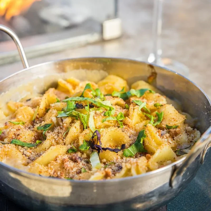 Creamy baked pasta in skillet with golden breadcrumbs and fresh herbs.