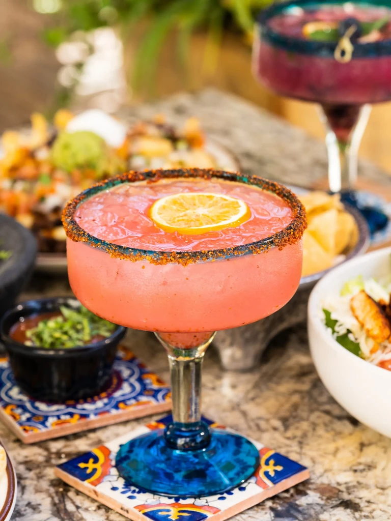 Vibrant red margarita with a spiced rim and citrus slice.