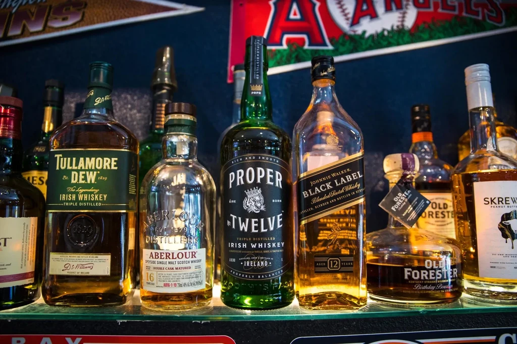 Well-lit glass shelf filled with various whiskey and scotch bottles.